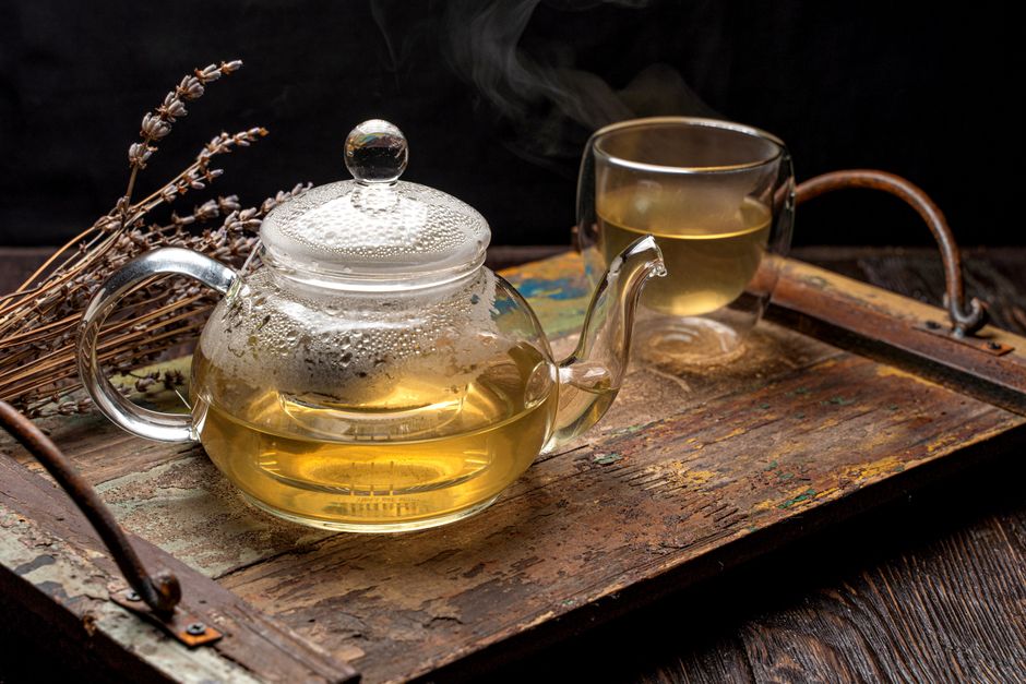 Gőzölgő tea csésze, száraz tealevelek és fahéjrudak egy fatálcán